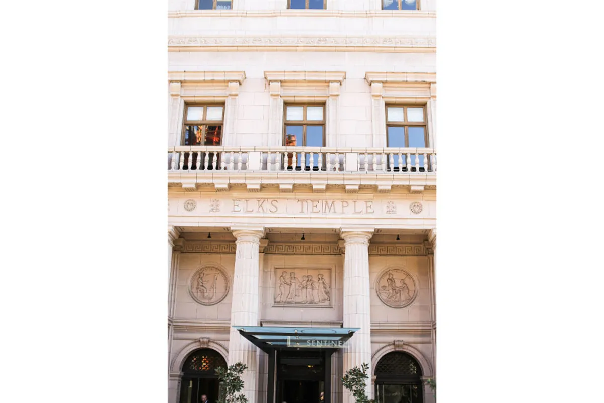 A grand exterior shot featuring the historic Elks Temple sign, ornate pillars, and intricate carvings. The scene highlights a culturally significant landmark, often a site for community events and cultural gatherings.