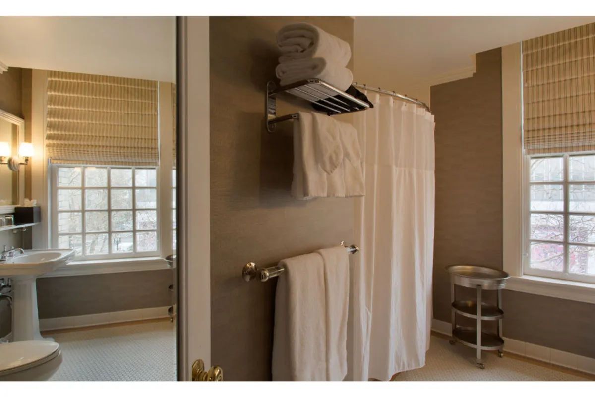 This image captures a serene bathroom filled with natural light, showcasing a shower curtain, a towel rack with neatly arranged towels, and the warmth of sunlight streaming through a window. The mood is refreshing and promotes self-care and relaxation.