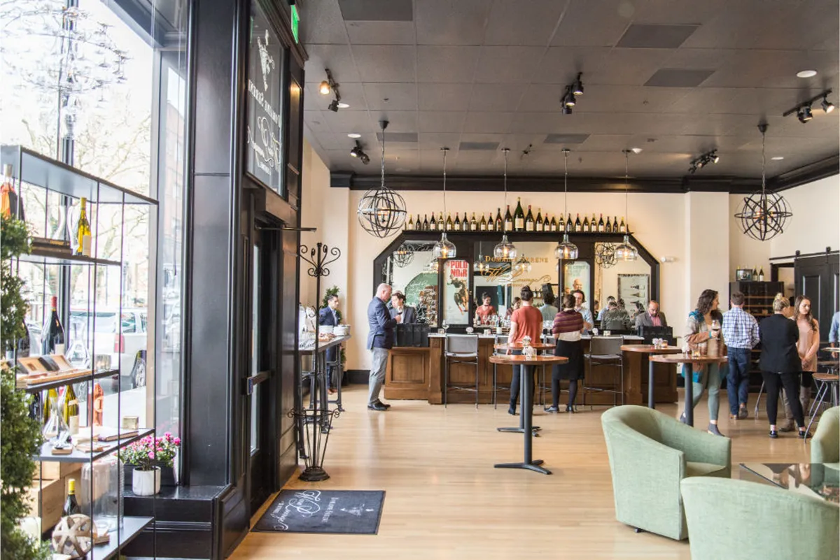 This image presents a lively bar area, featuring a well-stocked bar counter, hanging light fixtures, and a seating area. Wine bottles are prominently displayed, suggesting an inviting space for social gatherings and wine tasting events.